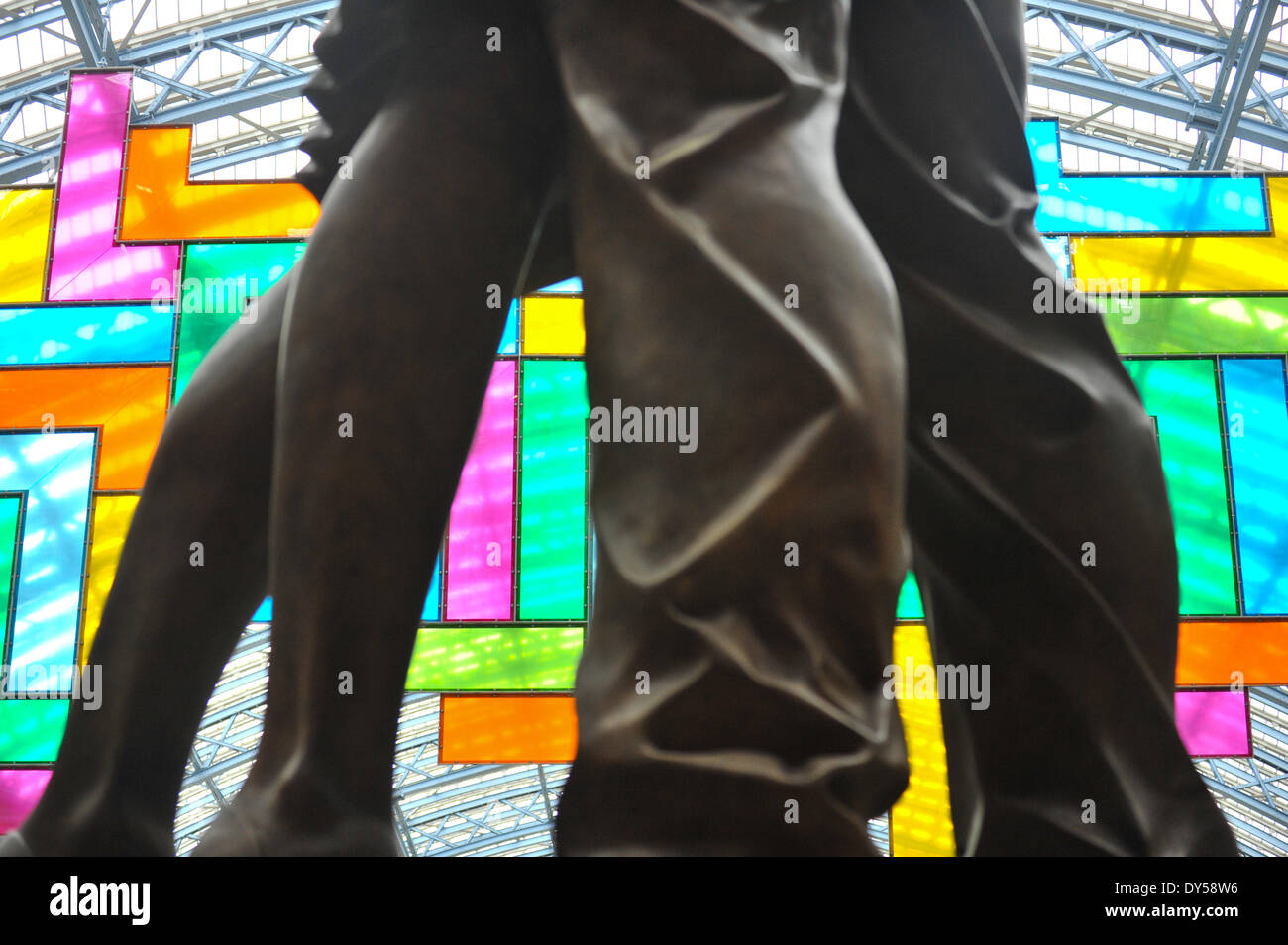 La stazione di St Pancras, London, Regno Unito. Il 7 aprile 2014. Guardando attraverso le gambe della scultura "L'Incontro" da Paolo giorno. Chromolocomotion, 20m x 10m lavori in mosaico fatto di 44 vivacemente colorati di perspex 'L' forme in una formazione geometrica appesi al soffitto della stazione di St Pancras. Credito: Matteo Chattle/Alamy Live News Foto Stock