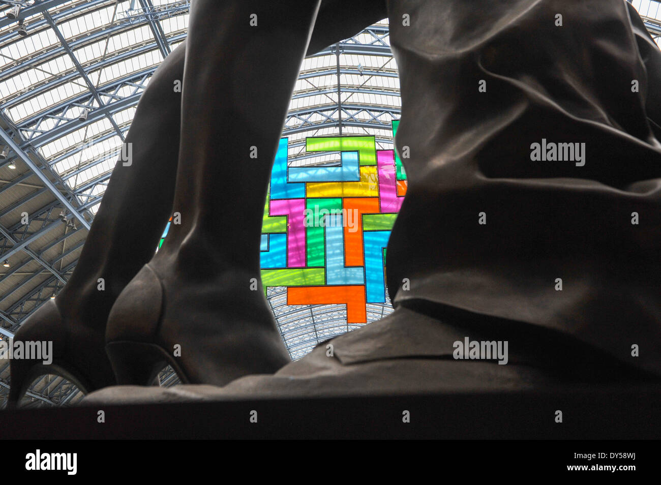 La stazione di St Pancras, London, Regno Unito. Il 7 aprile 2014. Guardando attraverso le gambe della scultura "L'Incontro" da Paolo giorno. Chromolocomotion, 20m x 10m lavori in mosaico fatto di 44 vivacemente colorati di perspex 'L' forme in una formazione geometrica appesi al soffitto della stazione di St Pancras. Credito: Matteo Chattle/Alamy Live News Foto Stock