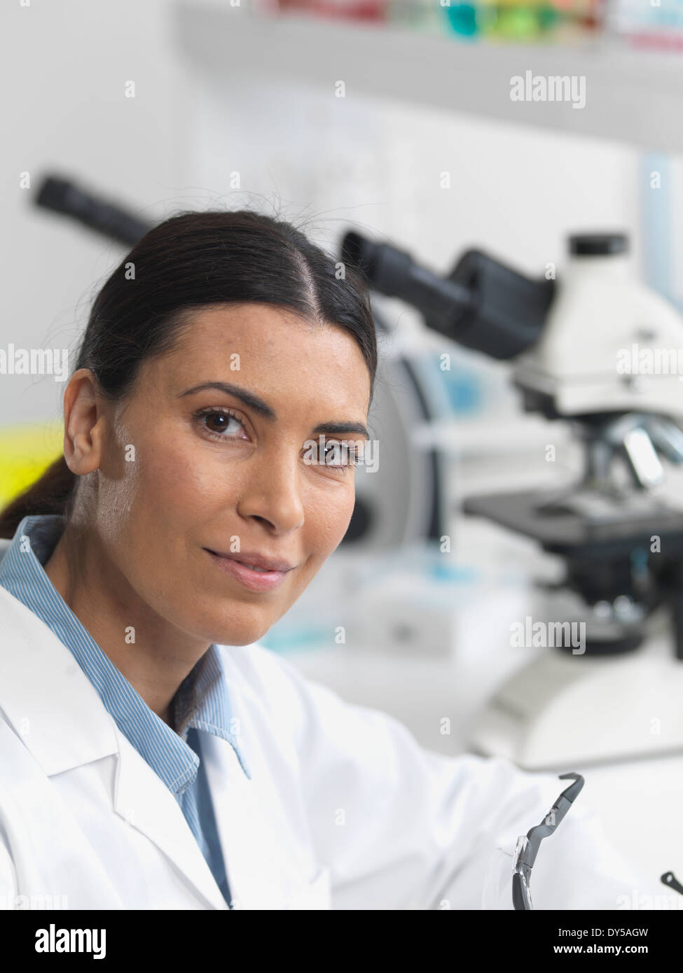 Ricercatore femmina in laboratorio accanto a microscopi. Foto Stock