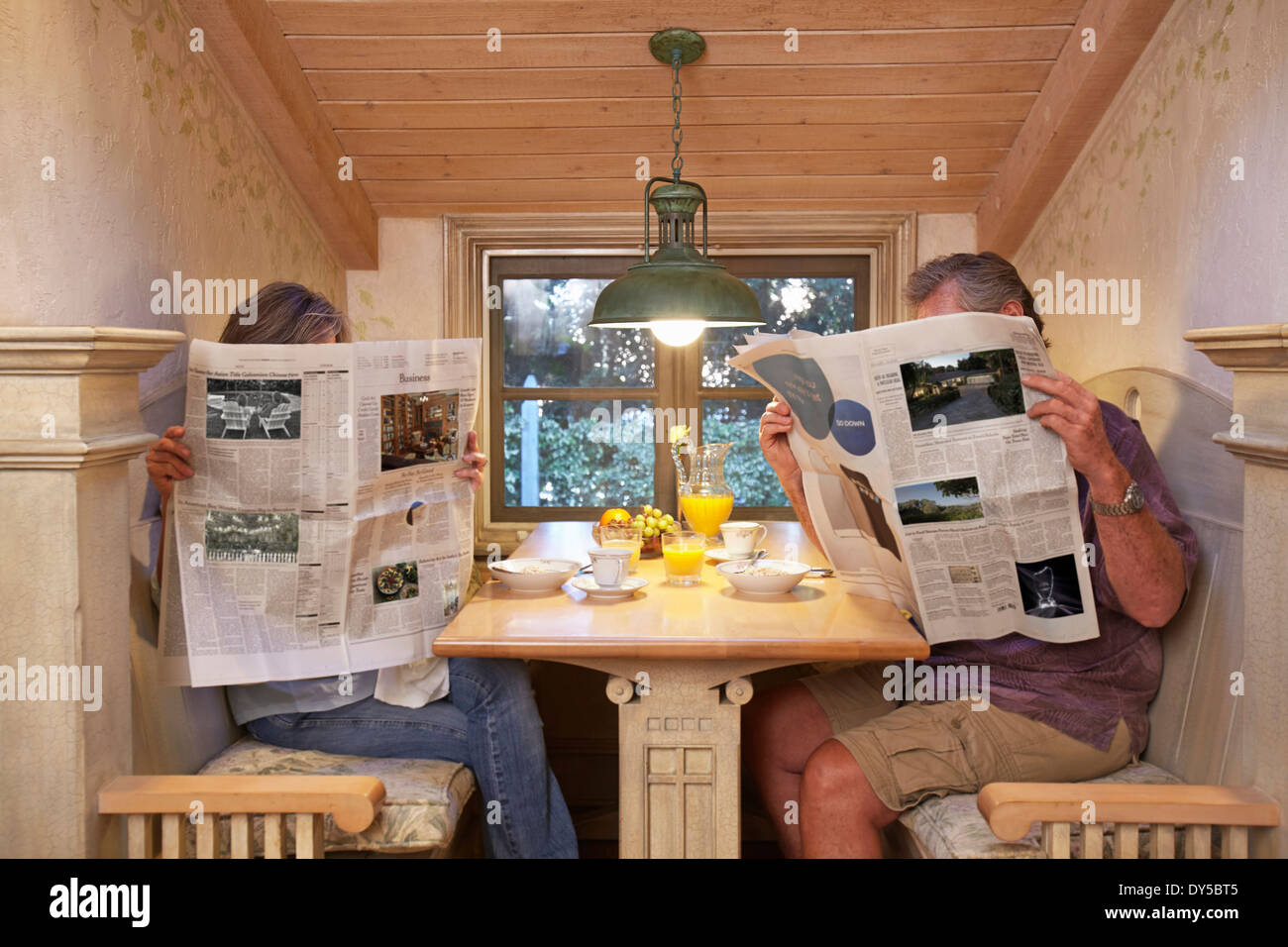 Coppia al tavolo per la colazione, ignorando ogni altro, leggendo i giornali Foto Stock