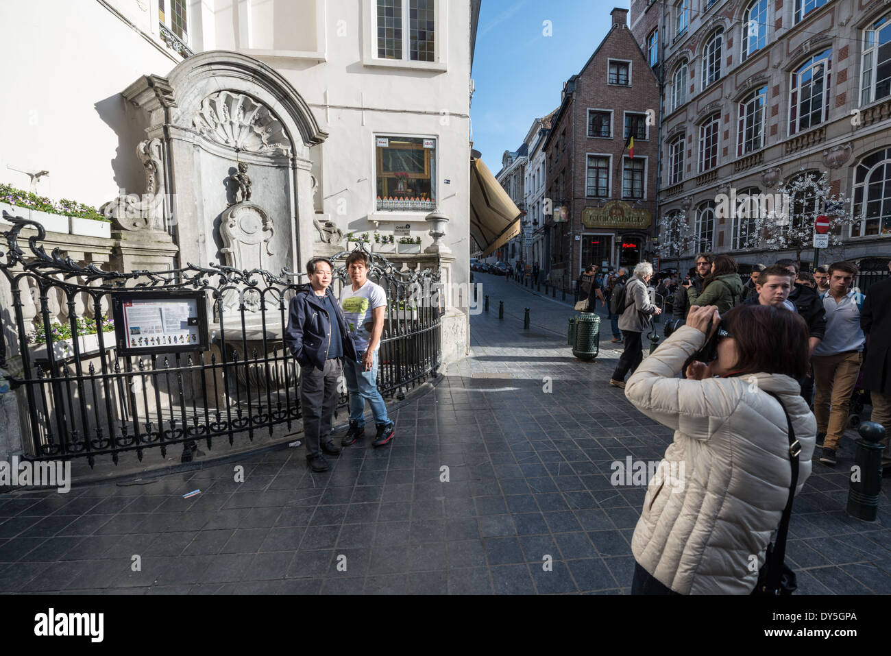 Fontana Manneken Pis turisti Bruxelles Belgio // BRUXELLES, Belgio — i turisti posano per le fotografie con la famosa fontana Manneken Pis all'angolo di Rue de l'Étuve/Stoofstraat. L'iconica statua in bronzo, una replica dell'originale di Hiëronymus Duquesnoy il Vecchio del 1619, rimane una delle località turistiche più popolari di Bruxelles per la fotografia. I visitatori si riuniscono in questo angolo storico per catturare immagini con la stravagante fontana che è diventata un simbolo del patrimonio culturale di Bruxelles. Foto Stock