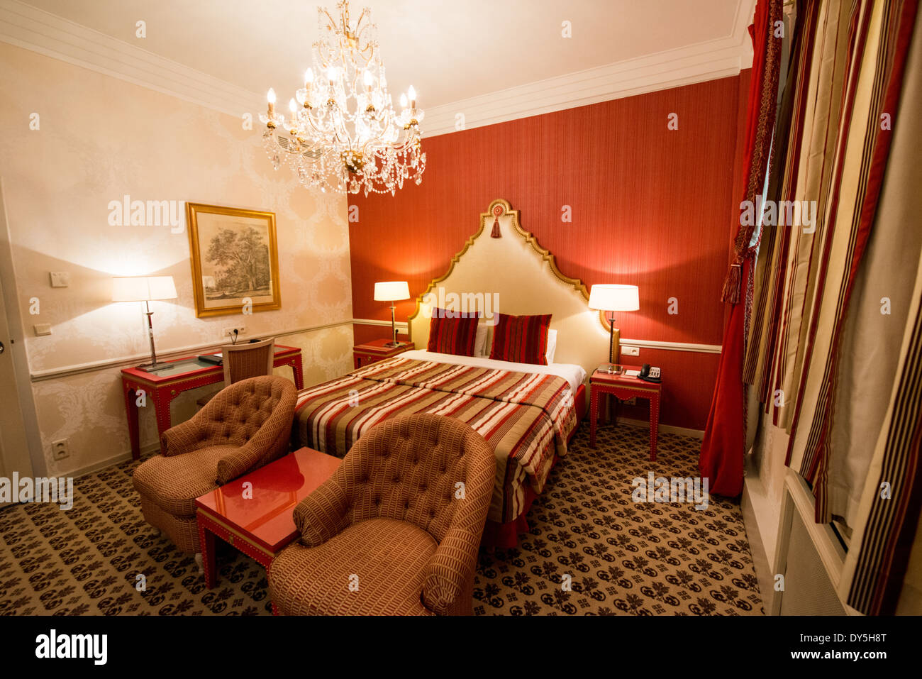 Camera Hotel Metropole Interior Bruxelles Belgio | BRUXELLES, Belgio - Una camera dell'Hotel Metropole abbina una scrivania laccata di rosso e un lampadario di cristallo con biancheria damascata a righe, che riflette le origini della Belle Époque dell'hotel. Inaugurato nel 1895, il Metropole è uno degli ultimi Grand hotel del XIX secolo in Europa ancora operativo sul suo sito originale. I suoi interni conservano gran parte degli ornamenti tipici dell'ospitalità di lusso tardo vittoriana. Foto Stock