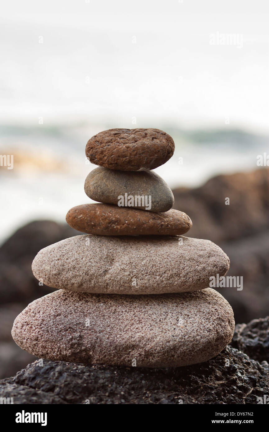 Piramide di pietre sulla sabbia che simboleggiano zen, armonia, equilibrio. Ocean in background Foto Stock