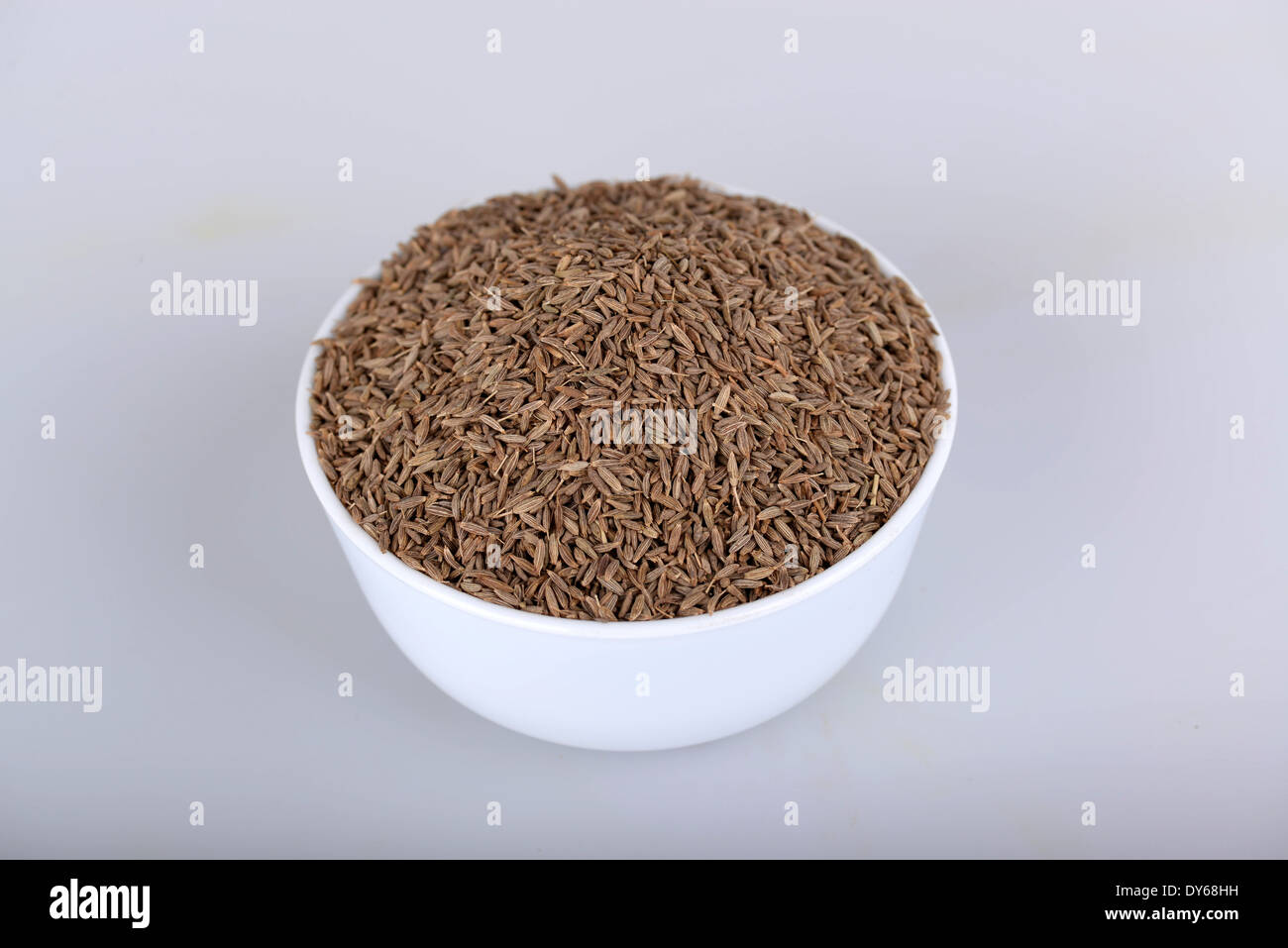 Semi di cumino nella tazza bianca con sfondo bianco Foto Stock