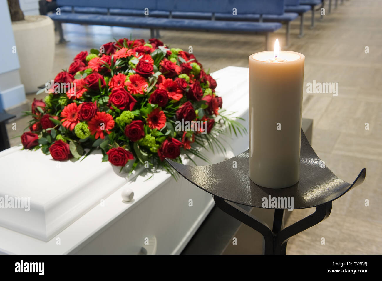 Una bara con un omaggio floreale in un obitorio e una candela che brucia nella parte anteriore Foto Stock