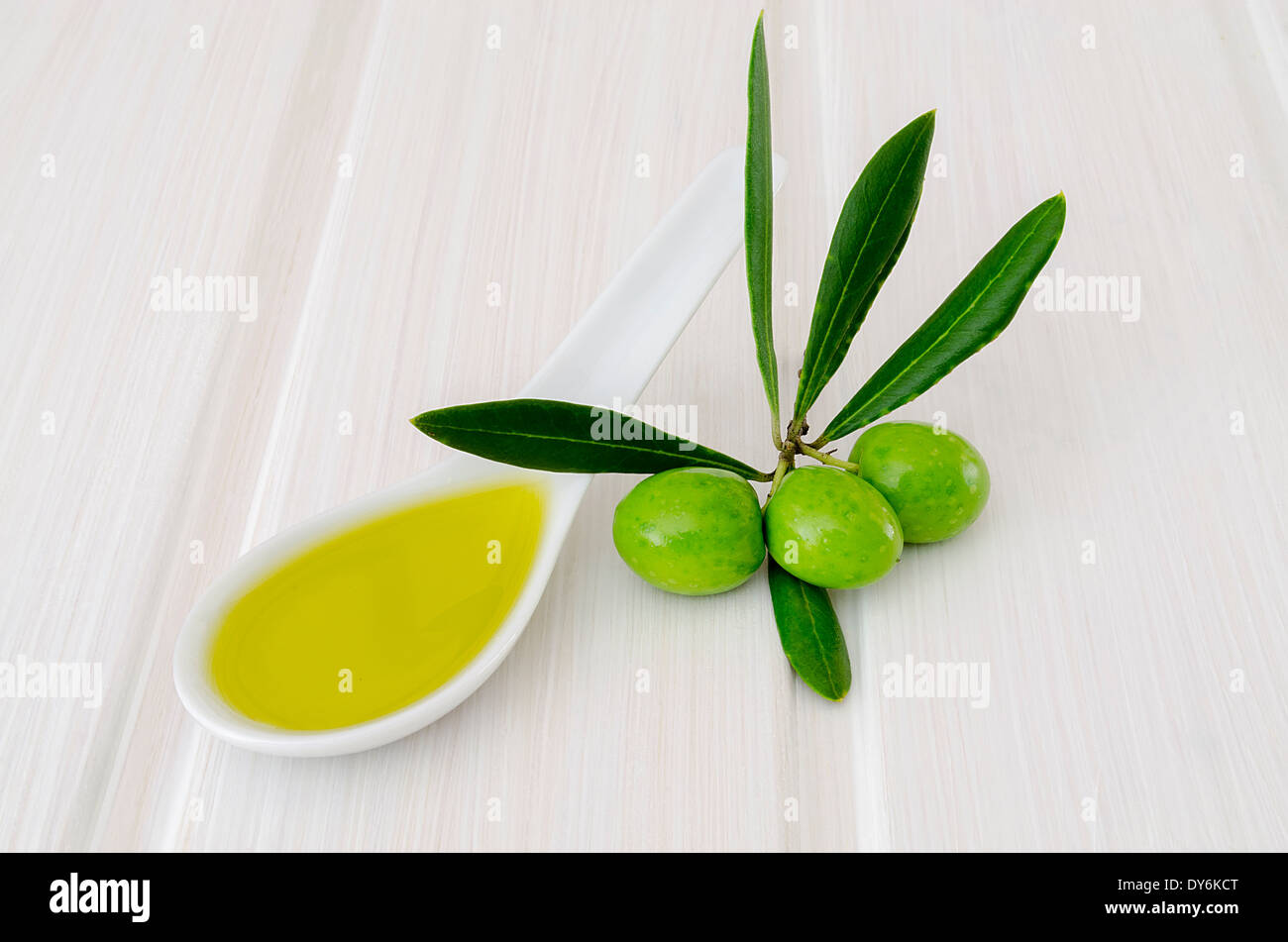 Cucchiaio con olio di oliva e di olive fresche isolato sul tavolo bianco Foto Stock
