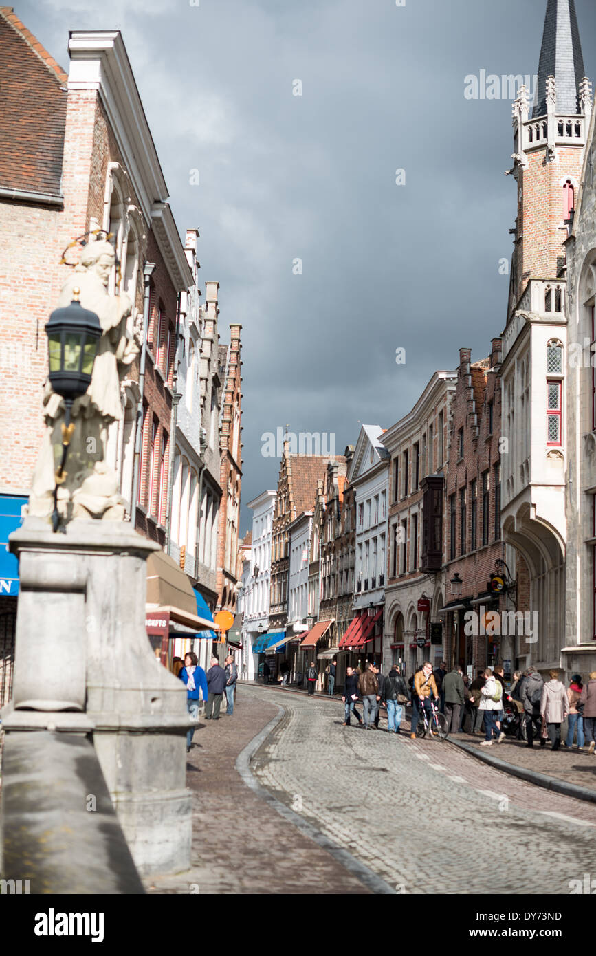 Wollestraat Medieval Street Bruges Belgio // BRUGES, Belgio — Wollestraat, una delle principali arterie medievali che conducono dalla centrale piazza Markt di Bruges, mantiene il suo carattere storico e la sua tradizione commerciale. Questa strada vitale esemplifica la pianificazione urbana medievale conservata del centro di Bruges. L'architettura storica e la disposizione delle strade dimostrano la continuità della vita urbana dall'epoca medievale a oggi. Foto Stock
