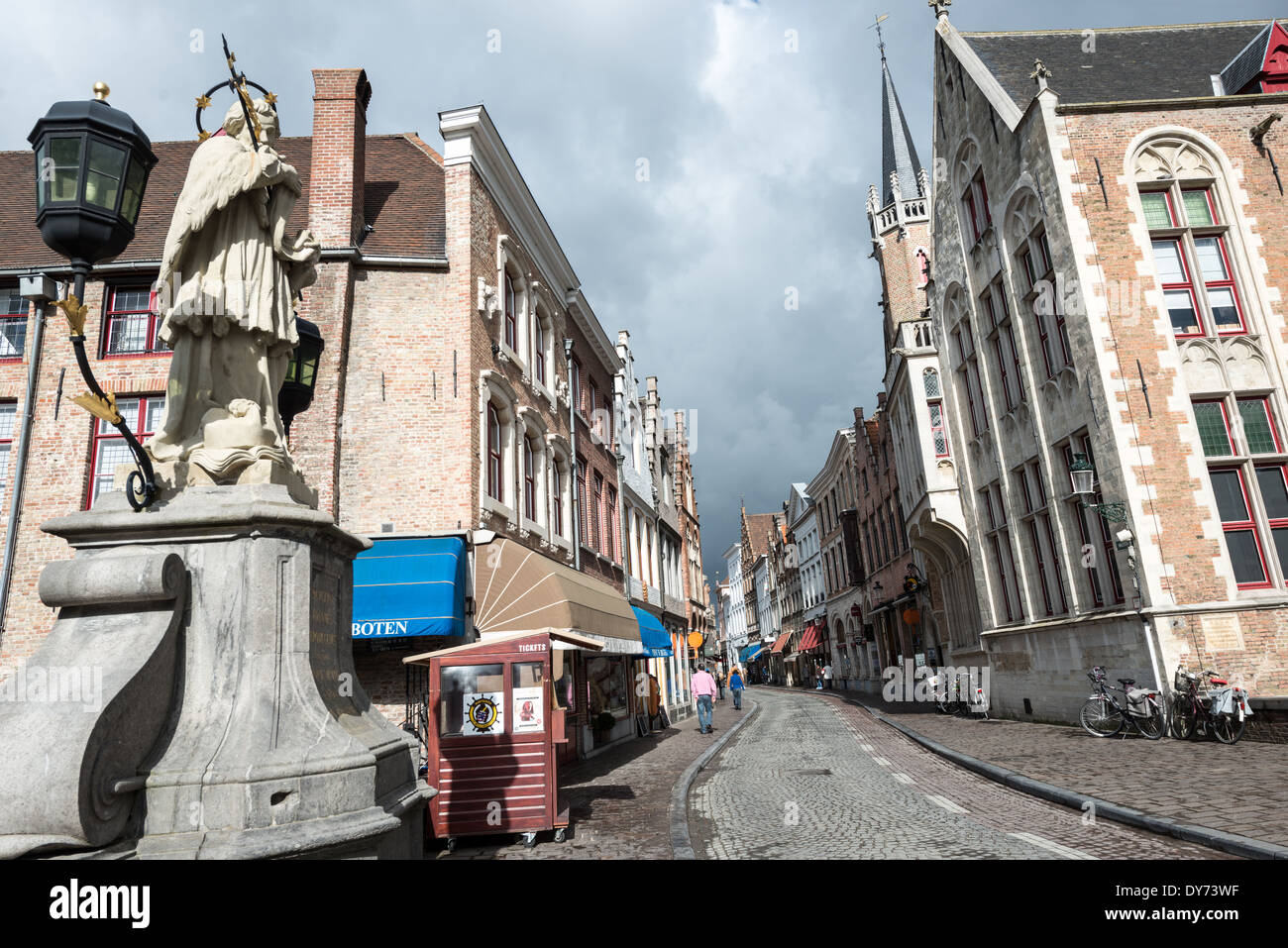Wollestraat Medieval Street Bruges Belgio // BRUGES, Belgio — Wollestraat, una delle principali arterie medievali che conducono dalla centrale piazza Markt di Bruges, mantiene il suo carattere storico e la sua tradizione commerciale. Questa strada vitale esemplifica la pianificazione urbana medievale conservata del centro di Bruges. L'architettura storica e la disposizione delle strade dimostrano la continuità della vita urbana dall'epoca medievale a oggi. Foto Stock