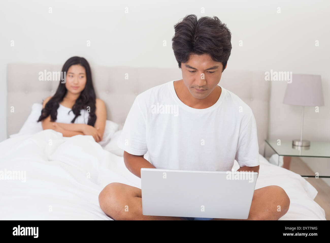 La donna a guardare il mio ragazzo utilizzando laptop sul fondo del letto Foto Stock