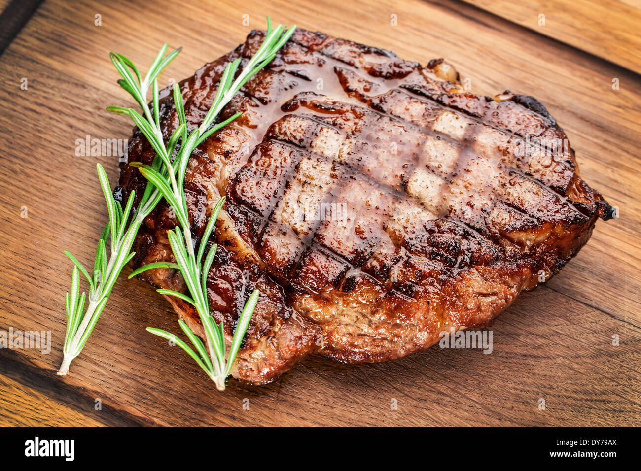 Bistecca di manzo con rosmarino su un tavolo di legno. Foto Stock