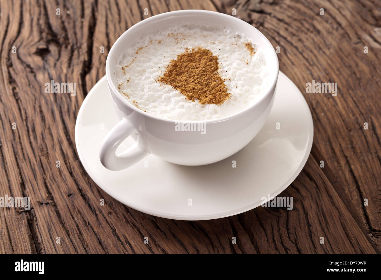 Tazza di cappuccino con cannella in polvere in forma di cuore sul vecchio tavolo in legno. Vista dall'alto. Foto Stock