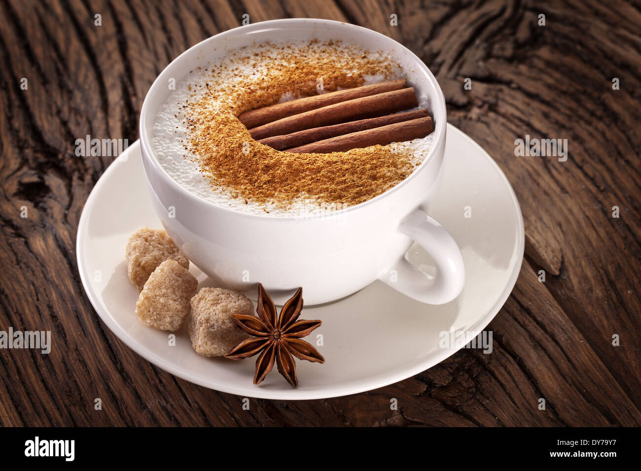 Tazza di cappuccino decorato con spezie e cubetti di zucchero di canna in prossimità di essa. Foto Stock