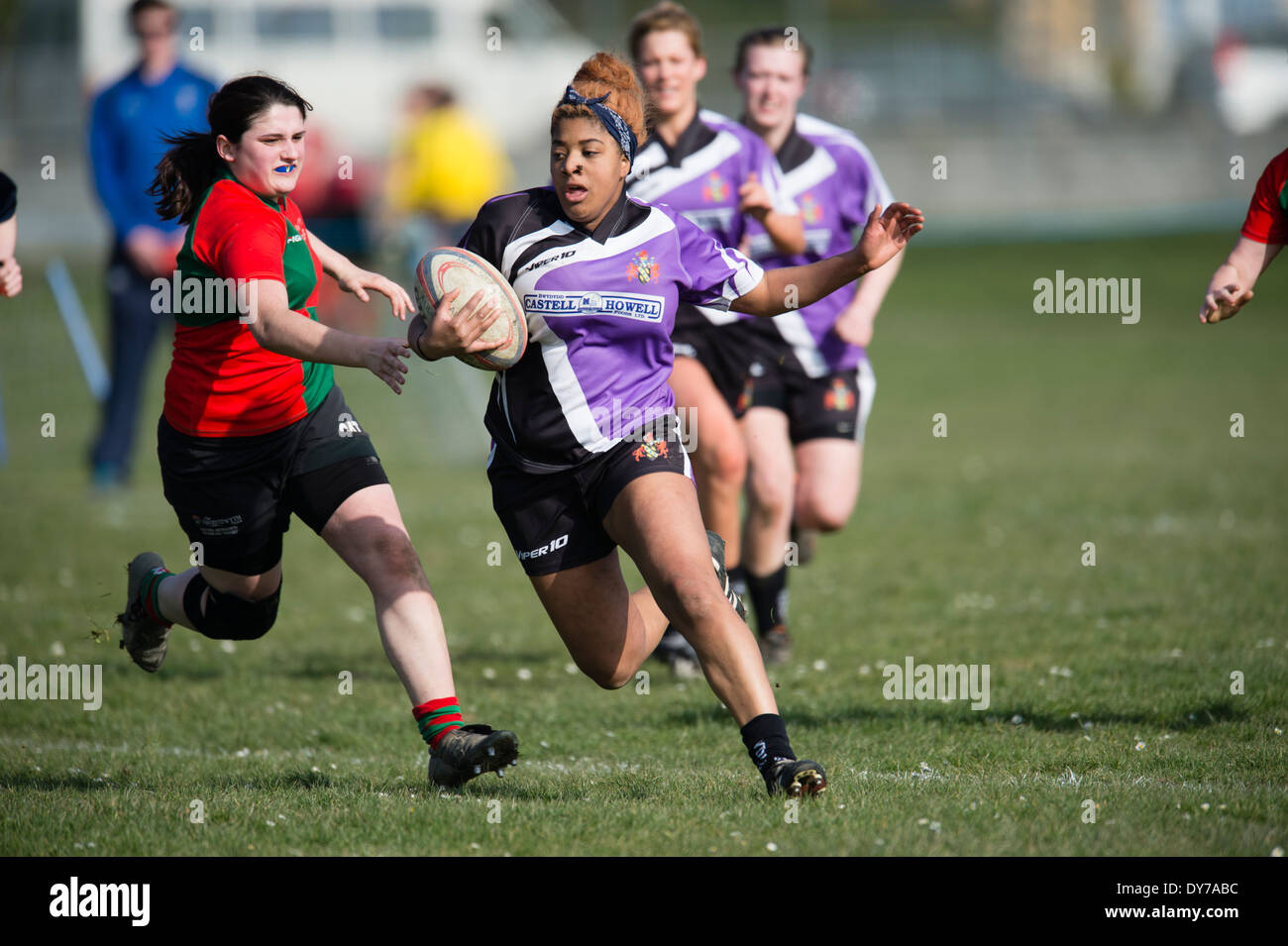 Aberystwyth university donne (in rosso e verde) giocando a rugby contro il Trinity St Davids university, Wales UK Foto Stock