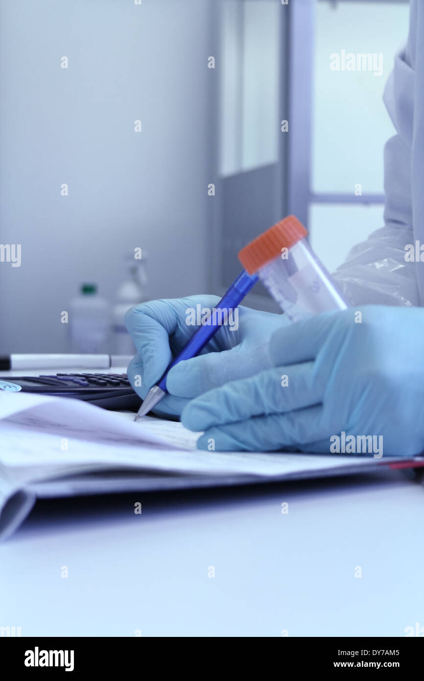 La mano del chimico con penna a scrivere le osservazioni in laboratorio Foto Stock