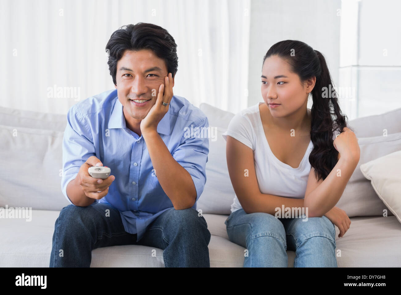 Donna seduta sul divano mentre fidanzato tv orologi Foto Stock