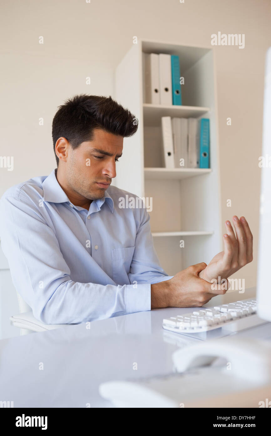 Imprenditore Casual toccando il suo polso dolente Foto Stock