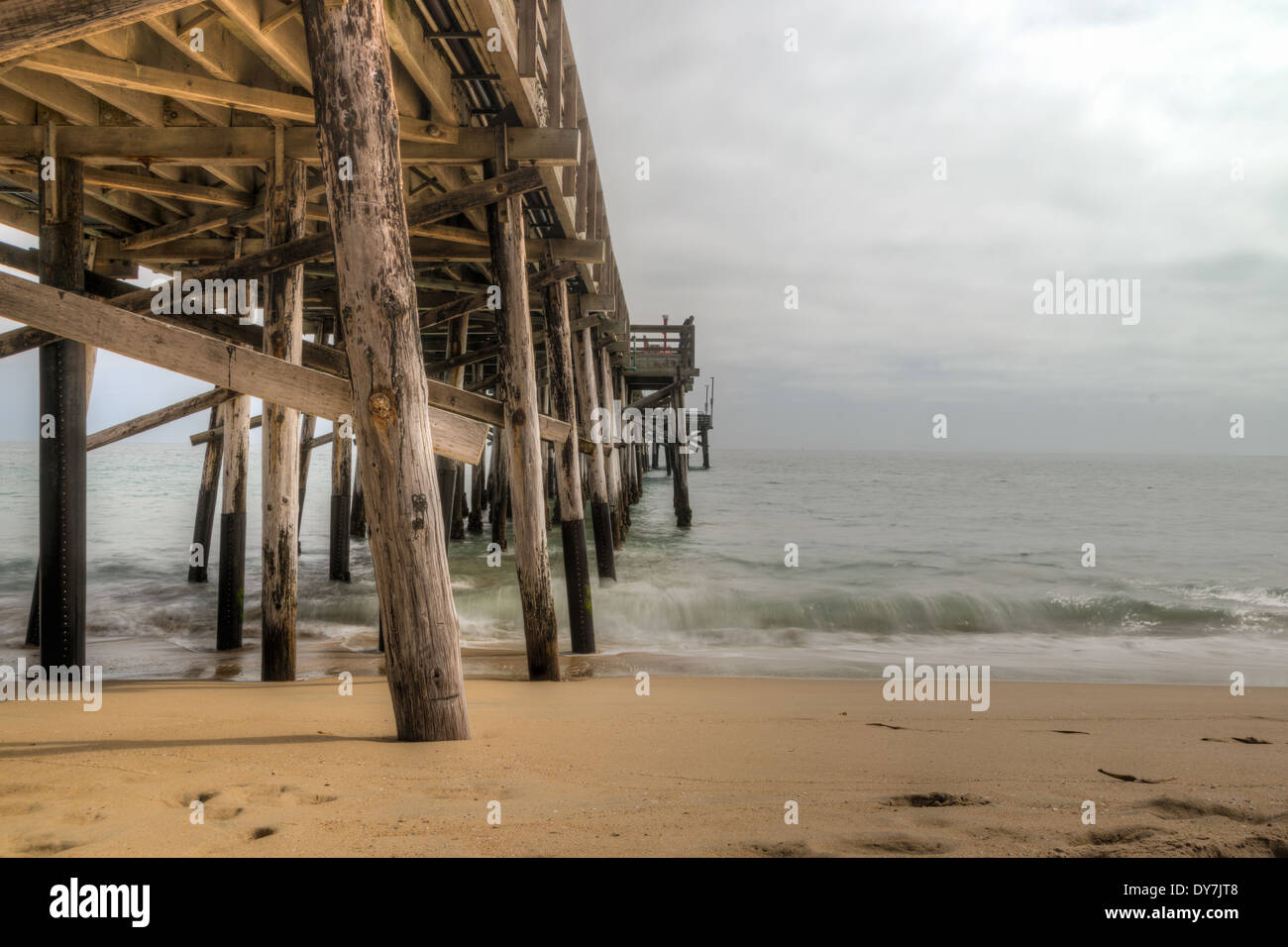 Una lunga esposizione cattura lenta onde in movimento sotto il Balboa Pier a scenic Newport Beach in California Foto Stock