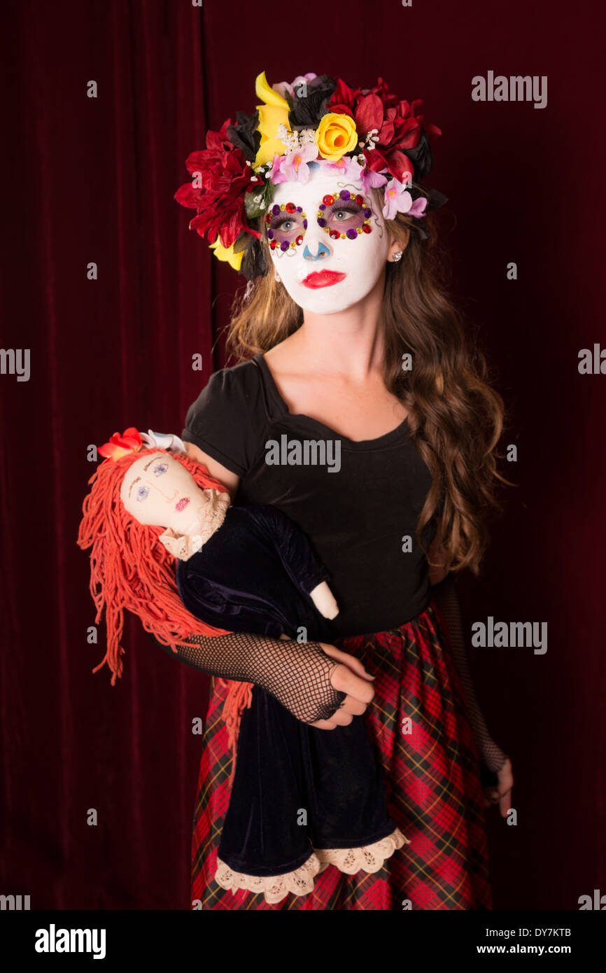 Il giorno dei morti la ragazza di make up, costume, e headress holding creepy doll Foto Stock