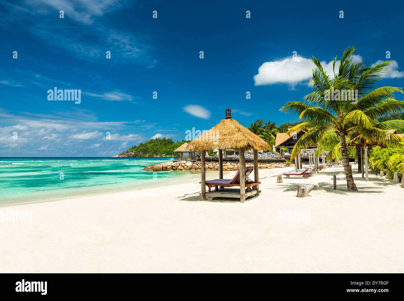 Lettini da spiaggia con tetto e mare turchese Foto Stock