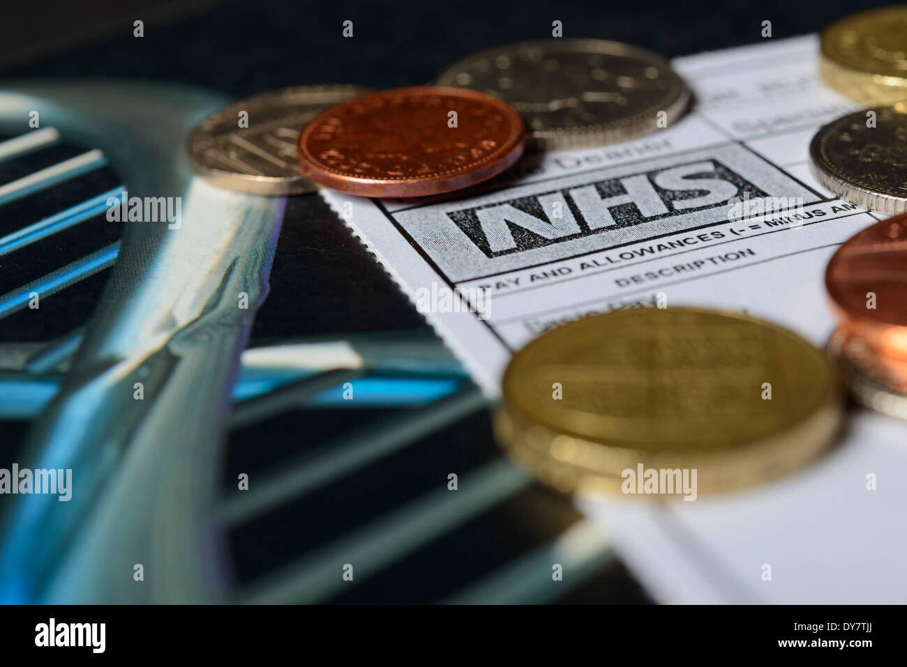 I medici di retribuzione - UN MEDICO DI NHS busta paga con monete su un medico di libro di testo. Contratto e pagare i negoziati nel concetto britannico. Foto Stock