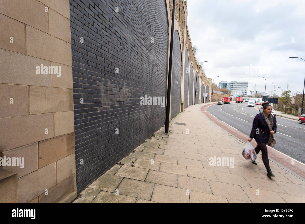Una donna sola a piedi lungo una strada di città, Sheffield, England, Regno Unito Foto Stock