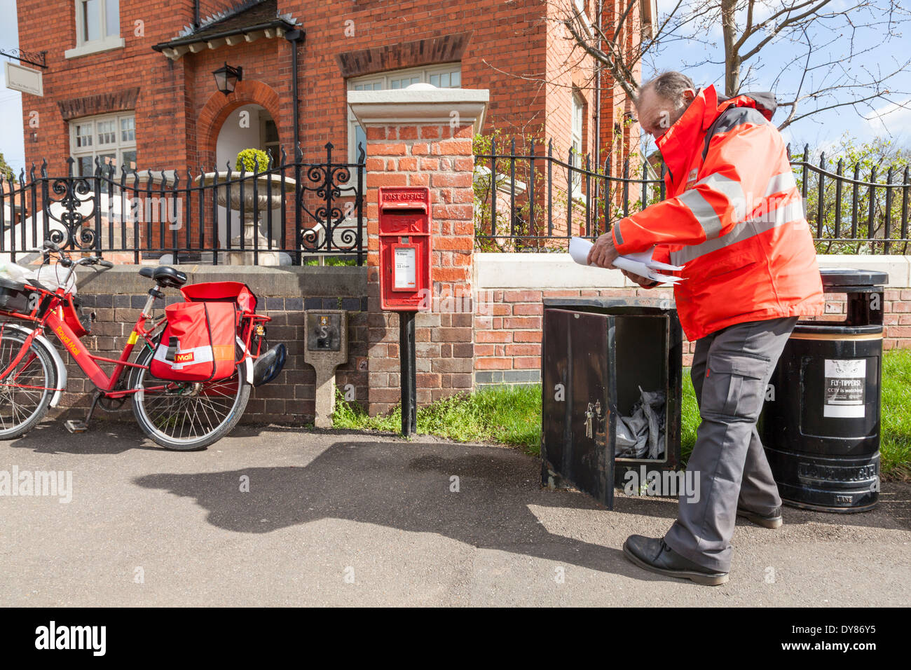 Regno Unito postino sul suo giro in una zona rurale, la raccolta e la consegna di posta da una casella al di fuori del Vecchio Ufficio Postale, Plumtree, Nottinghamshire, England, Regno Unito Foto Stock