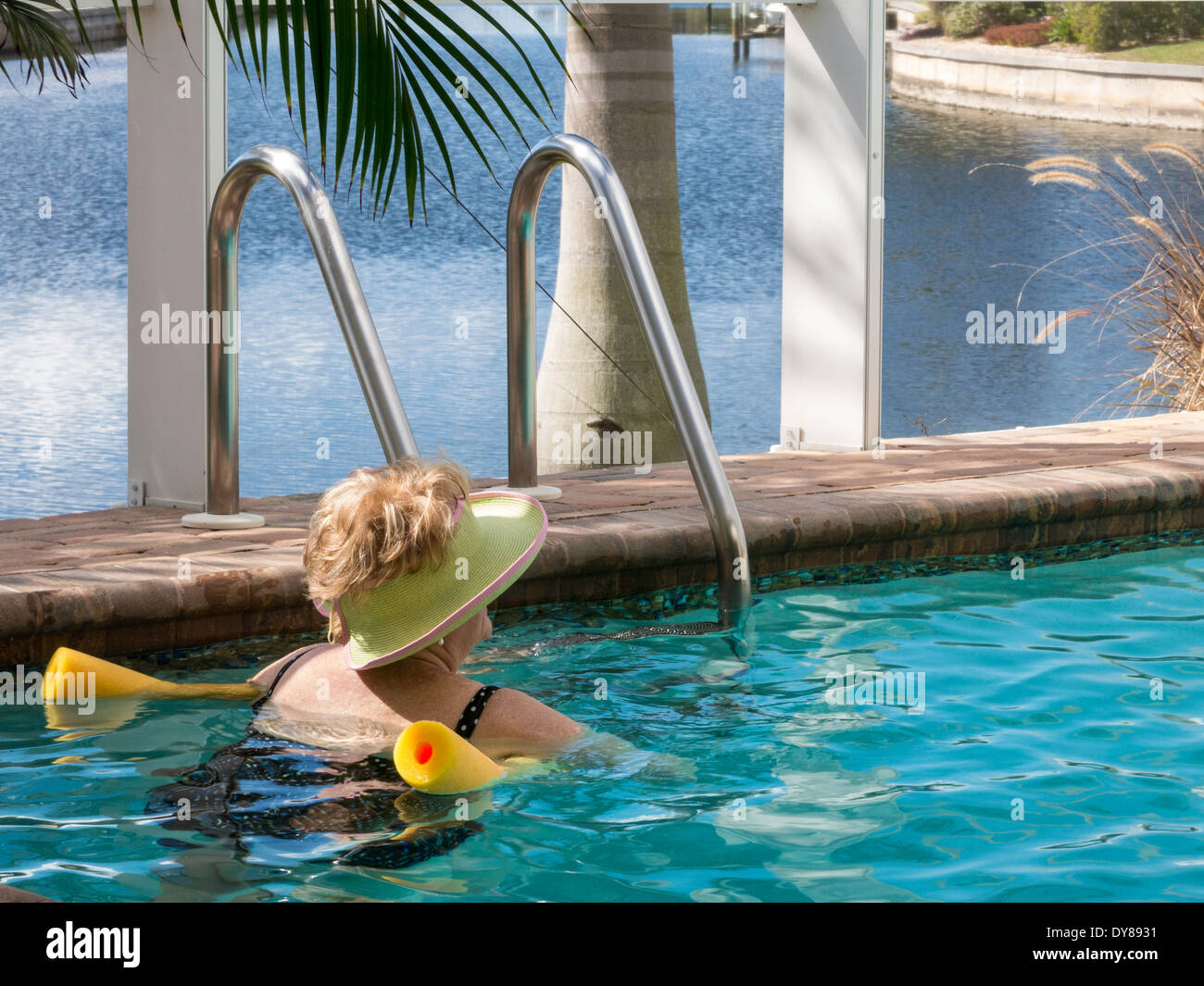 Donna matura di oziare in piscina con piscina a base di noodle, Florida, Stati Uniti d'America Foto Stock
