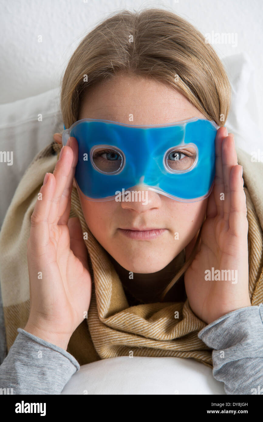 Giovane donna ha una sbornia, i suoi occhi raffreddato con una maschera di raffreddamento Foto Stock