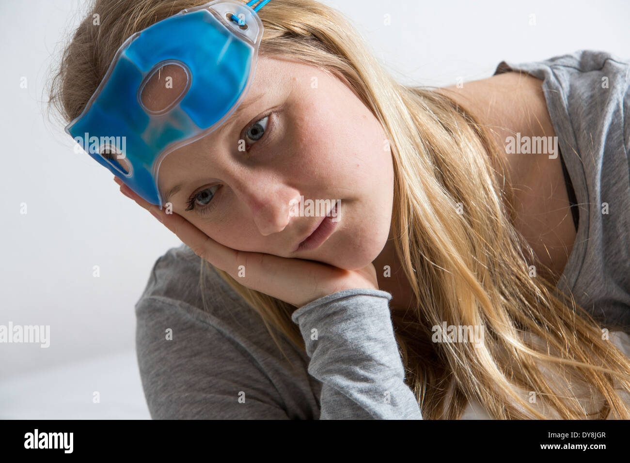 Giovane donna ha una sbornia, i suoi occhi raffreddato con una maschera di raffreddamento Foto Stock