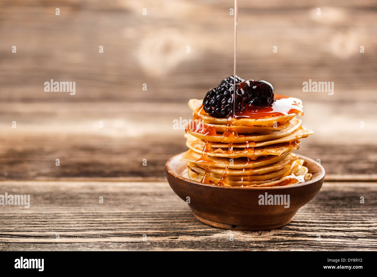 Il miele versando sopra una pila di mini pancake Foto Stock