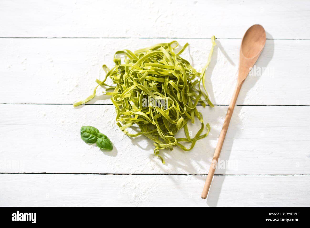 Tagliatelle fresche, spinaci foglie di basilico, il cucchiaio di legno e farina bianca sul tavolo di legno Foto Stock