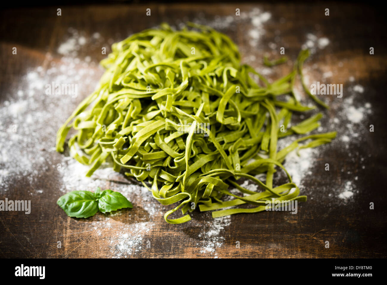 Tagliatelle fresche, spinaci foglie di basilico e la farina a fontana sul tavolo di legno Foto Stock