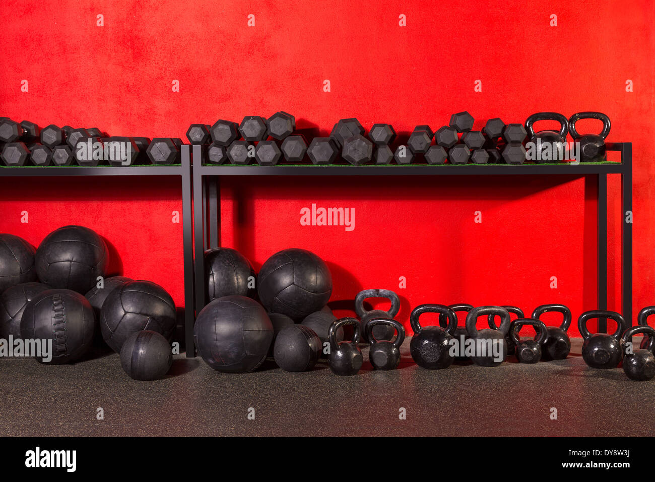 Kettlebell dumbbell e ponderati slam palle peso attrezzatura di allenamento alla palestra pareti rosse Foto Stock