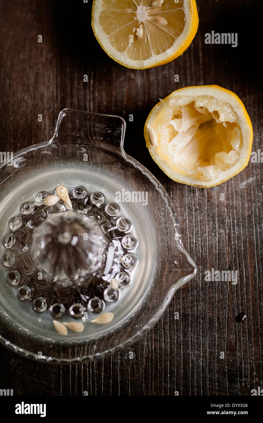 Halfs di limone spremuto, spremitore di limone con il succo sul tavolo di legno Foto Stock