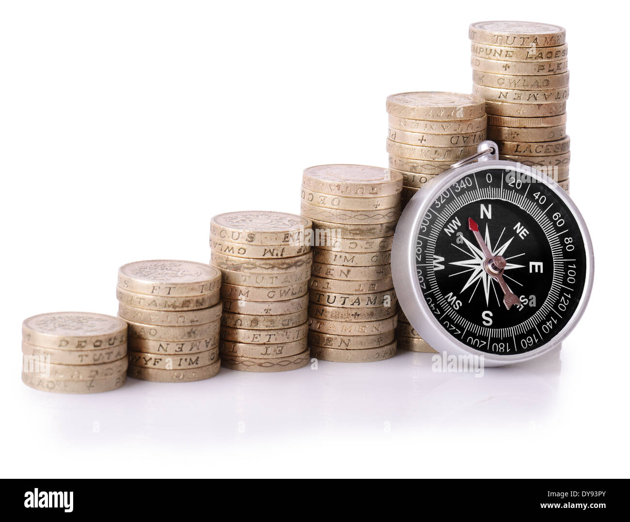 Compass appoggiata su un aumento di pile di monete metalliche isolate su uno sfondo bianco Foto Stock