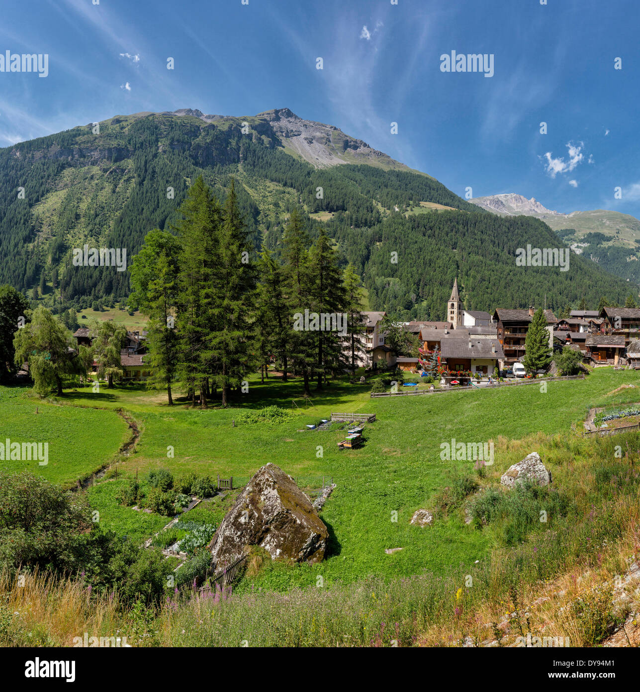 Villaggio di montagna città chiesa del villaggio prato campo alberi estate montagne colline Evolene Val d'Herens Wallis Switzerlan Vallese Foto Stock