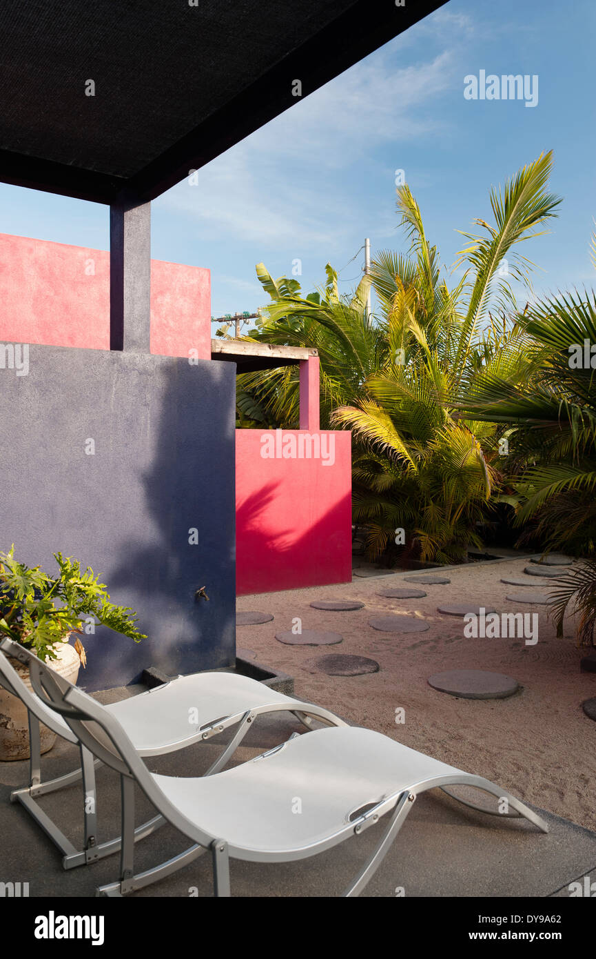 Moderne sedie a sdraio sulla terrazza che si affaccia sul cortile rotondo con pietre per pavimentazione e impianti di Palm Foto Stock