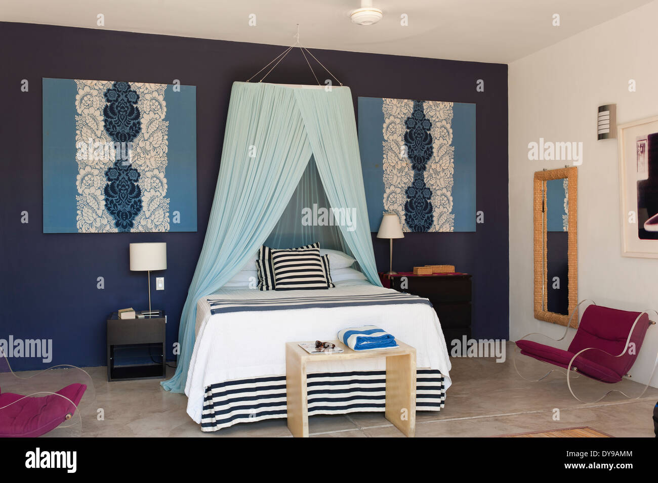 Letto matrimoniale con baldacchino netto in blu camera da letto murato con iconico moderne poltrone Foto Stock