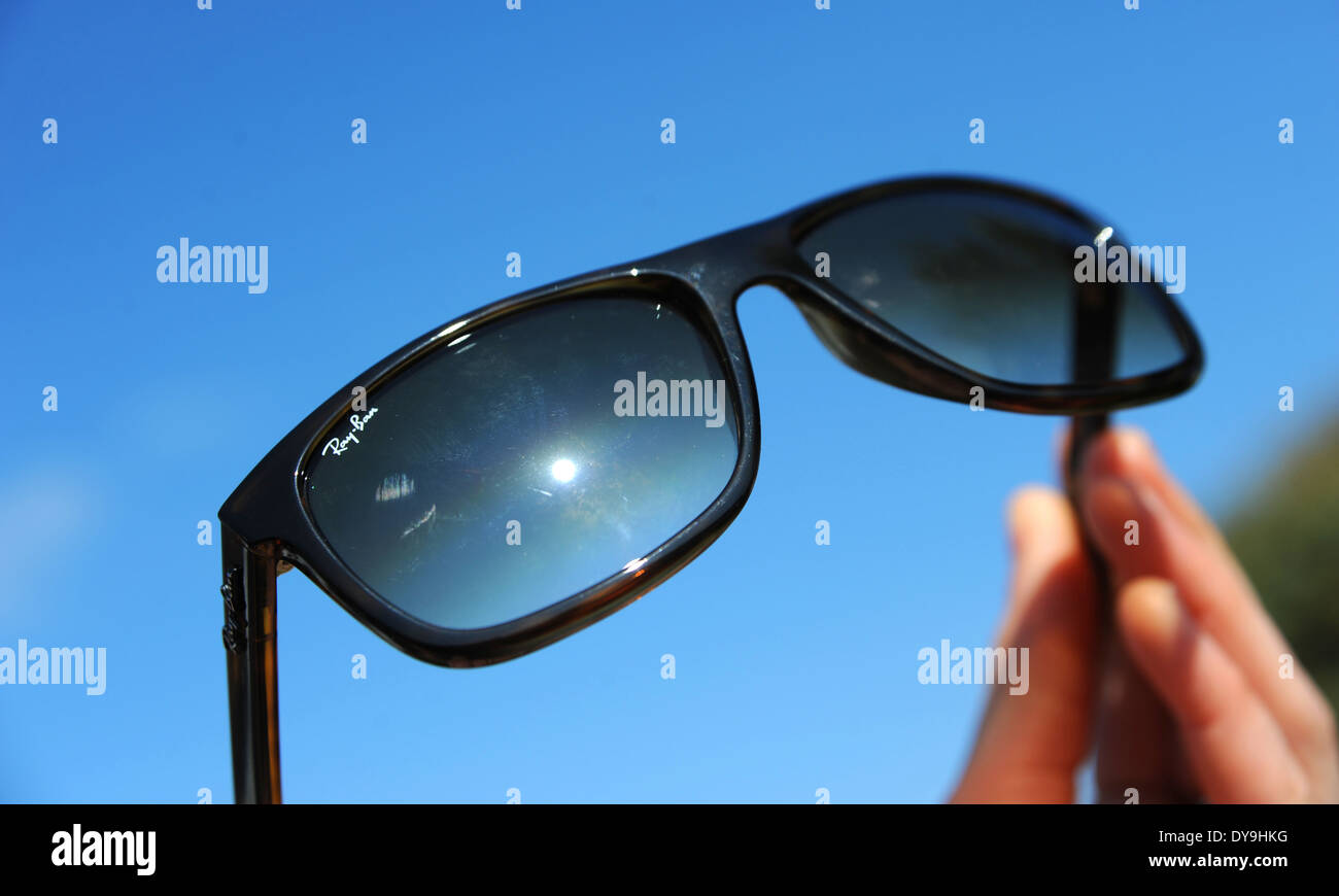 Ray Ban occhiali da sole essendo trattenuto contro il Cielo di estate blu Foto Stock