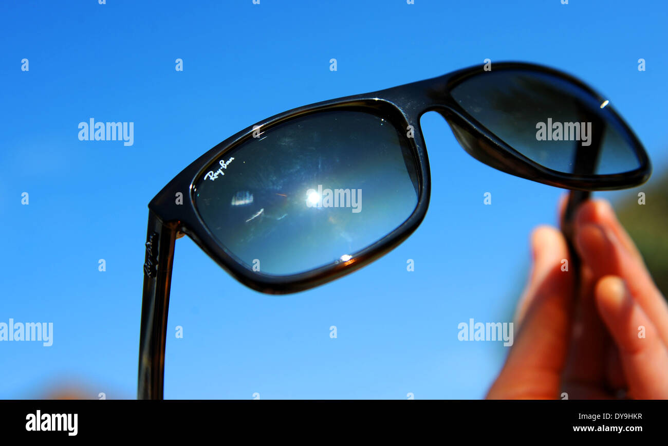 Ray Ban occhiali da sole essendo trattenuto contro il Cielo di estate blu Foto Stock