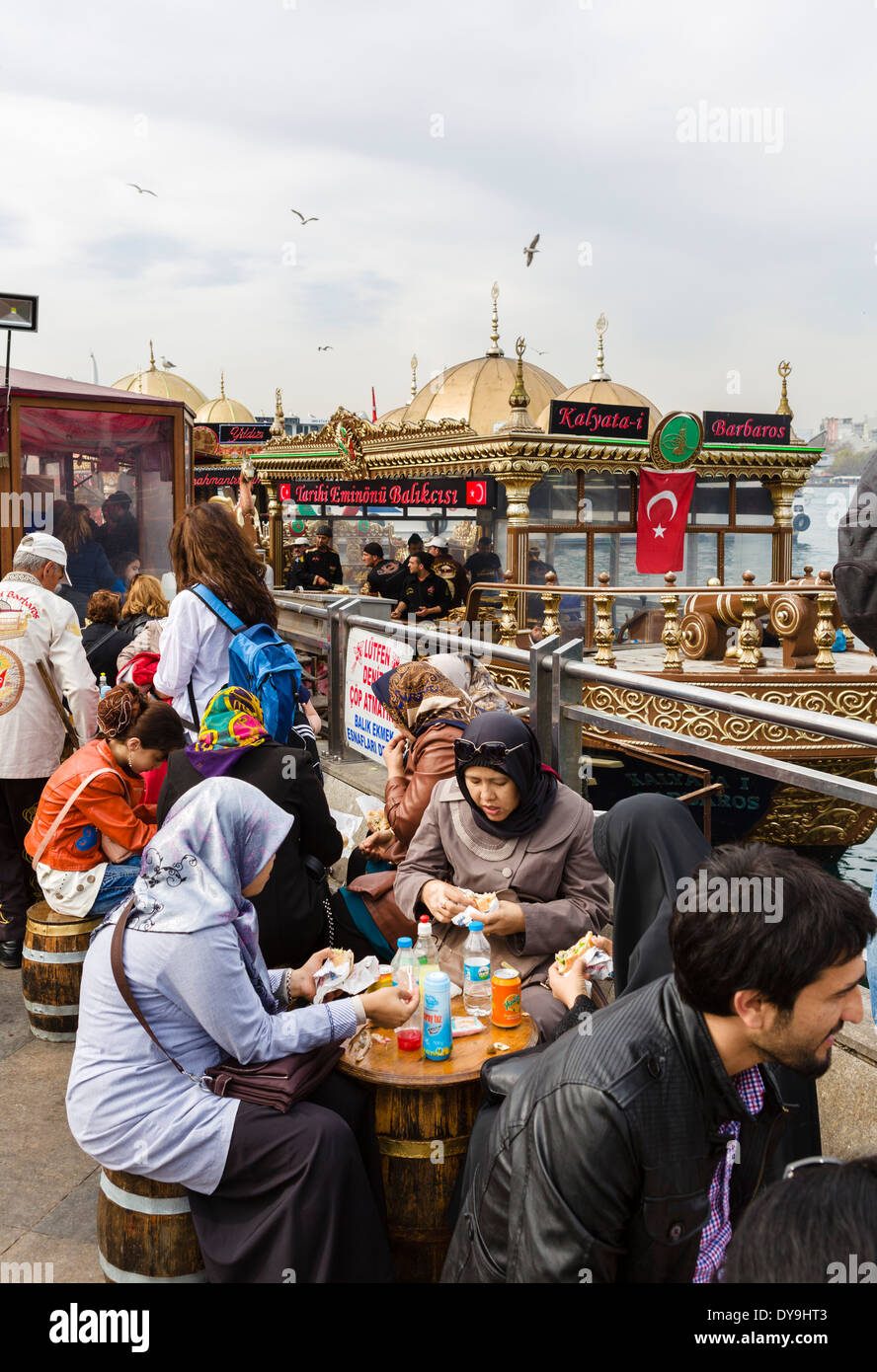 La gente del posto e turisti di mangiare da imbarcazioni di vendita del pesce panini vicino al Ponte di Galata, quartiere Eminonu, Istanbul, Turchia Foto Stock