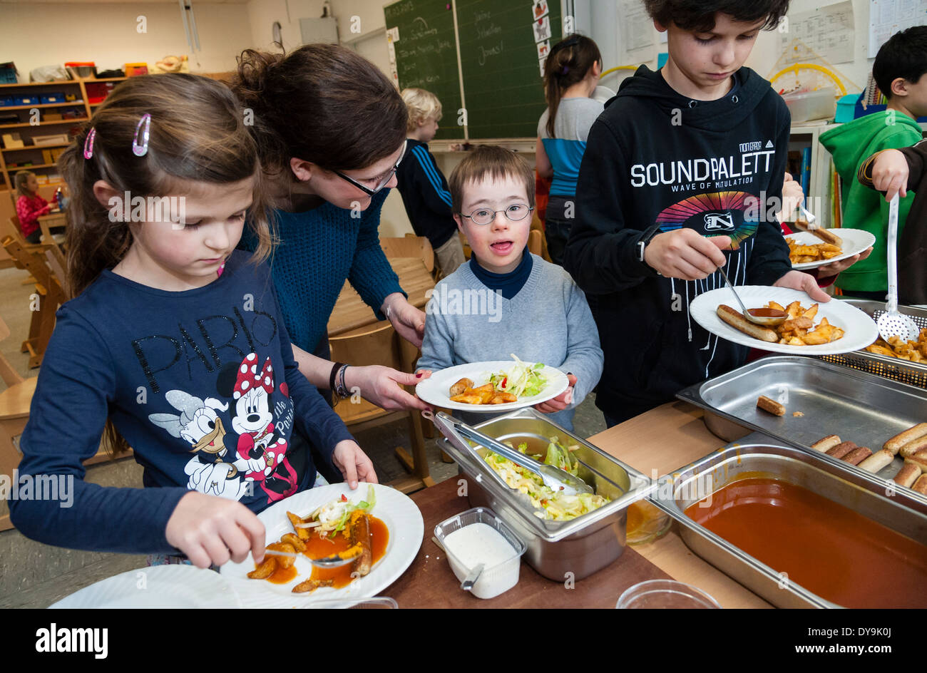 Non-disabili e gli alunni disabili (in questo caso un ragazzo che soffre di sindrome di Down) pranzare insieme nella loro classe. Foto Stock