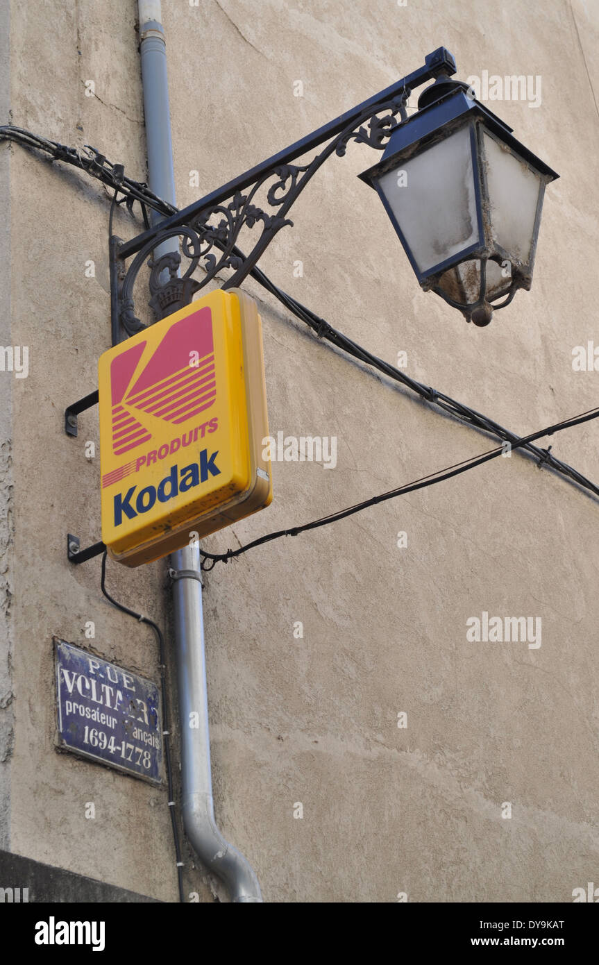 Lampione, kodak illuminato pubblicità segno e francese in smalto blu strada segno sulla parete a Arles Francia Foto Stock