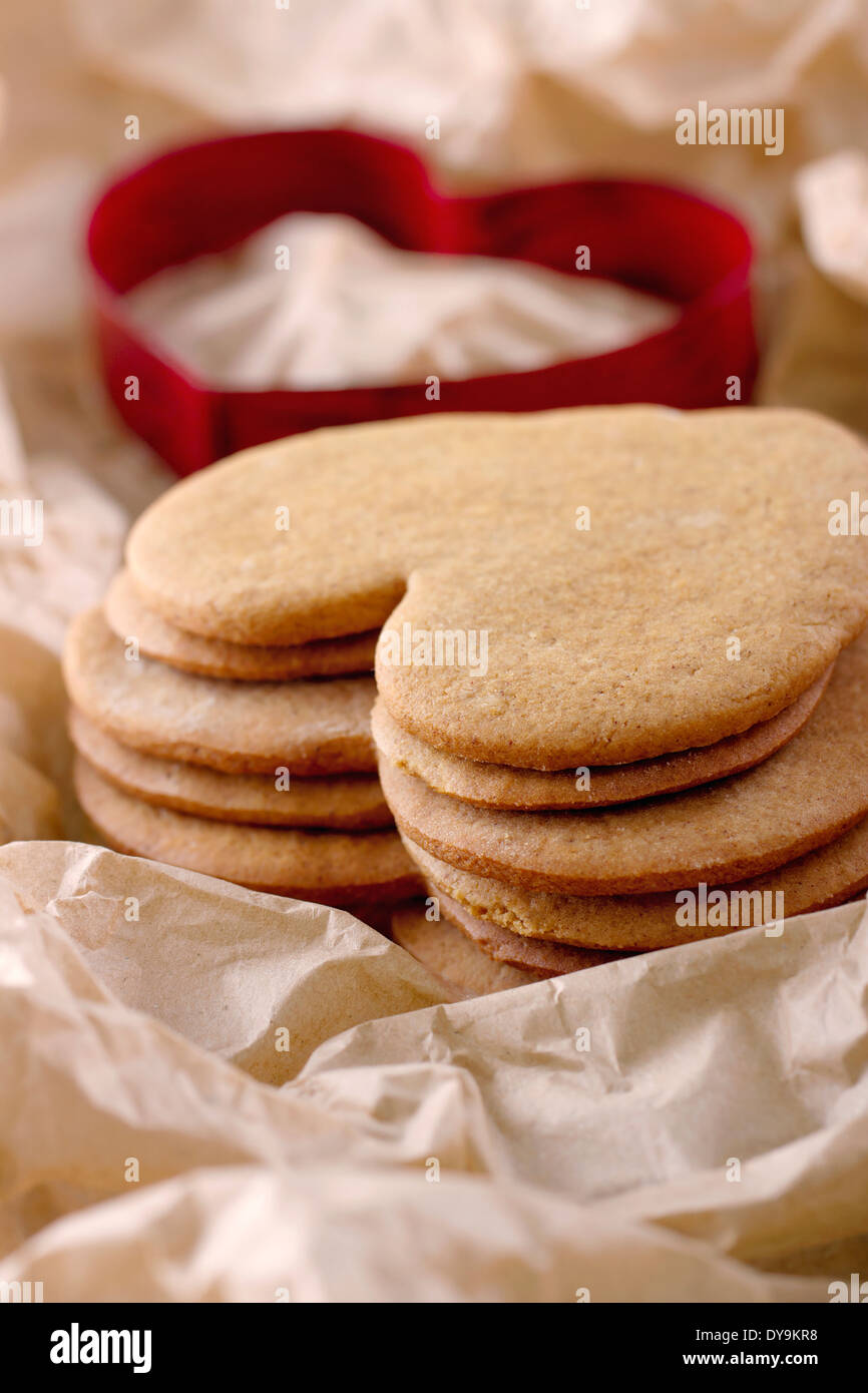 Rosso a forma di cuore cookie cutter e una pila di marrone in casa natale gingerbread cookie Foto Stock