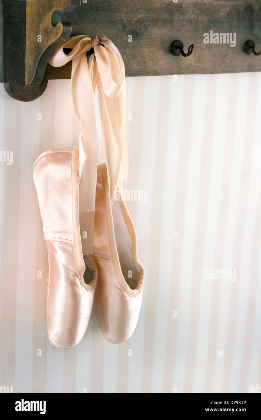 Color crema ballet pointe shoes sospesi dal rack in legno con carta da parati a strisce per spazio di copia Foto Stock