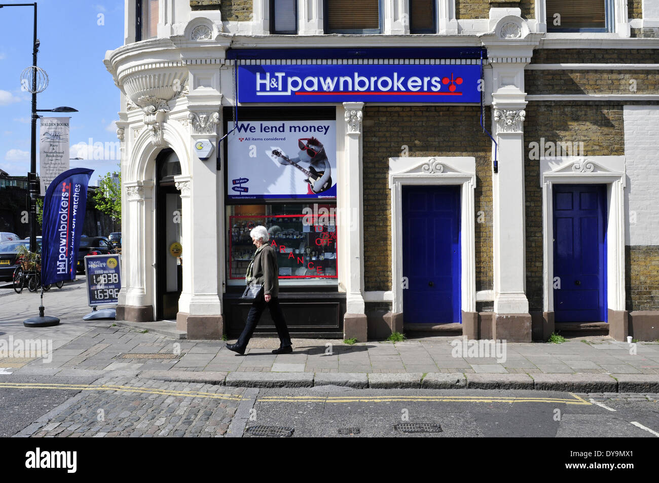 Una donna cammina passato H&T pawnbrokers shop, London, Regno Unito Foto Stock