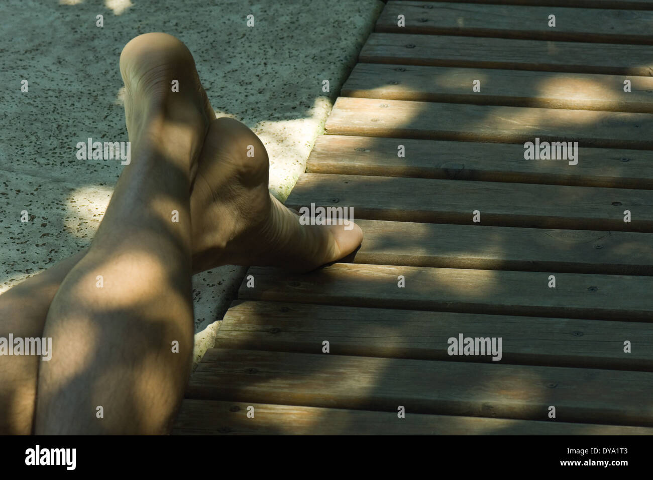 Uomo disteso su un deck di gambe incrociate alla caviglia, ritagliato Foto Stock