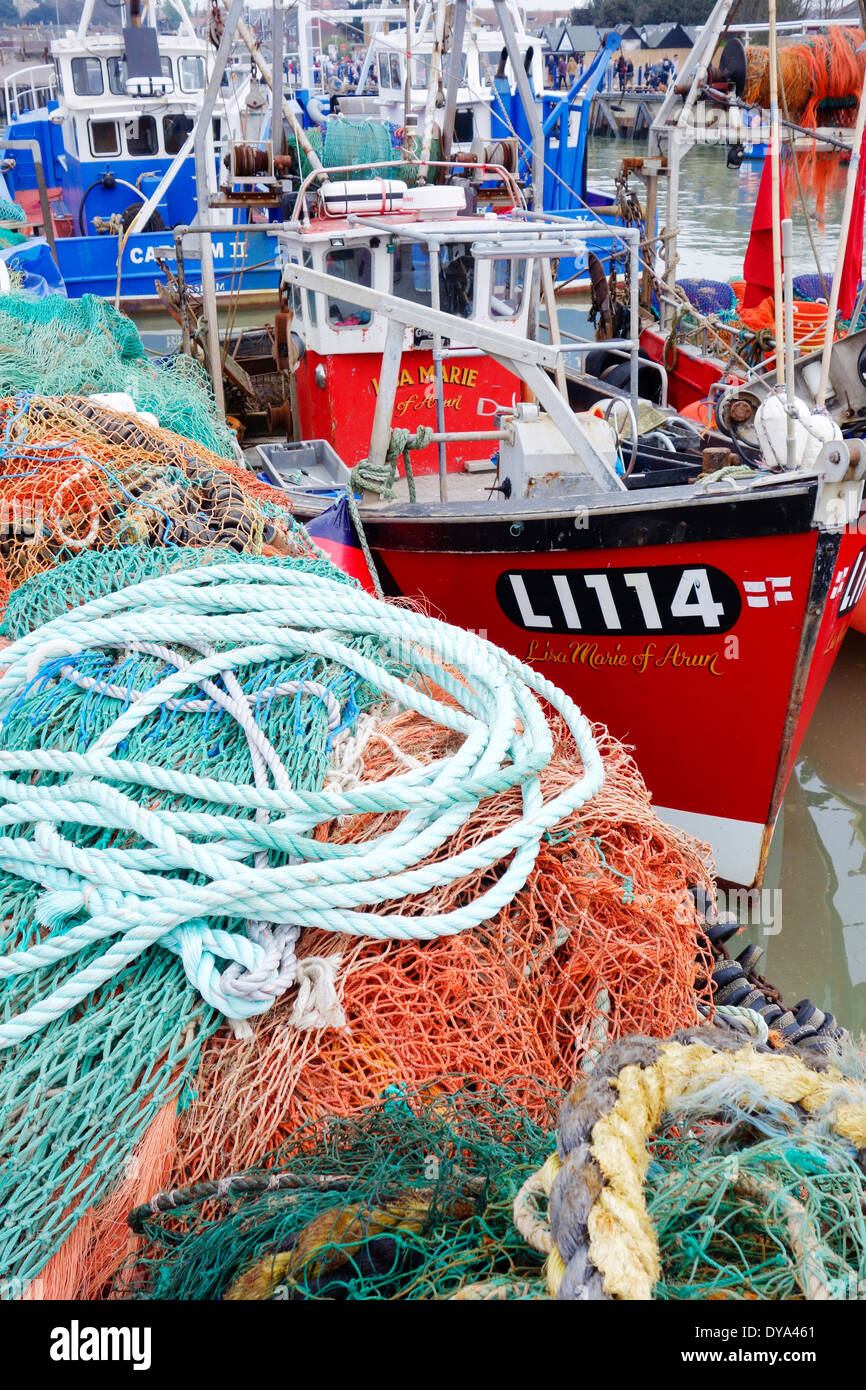 Regno Unito, Inghilterra, Whitstable. Le reti da pesca e le navi per la pesca a strascico ormeggiata in porto Foto Stock