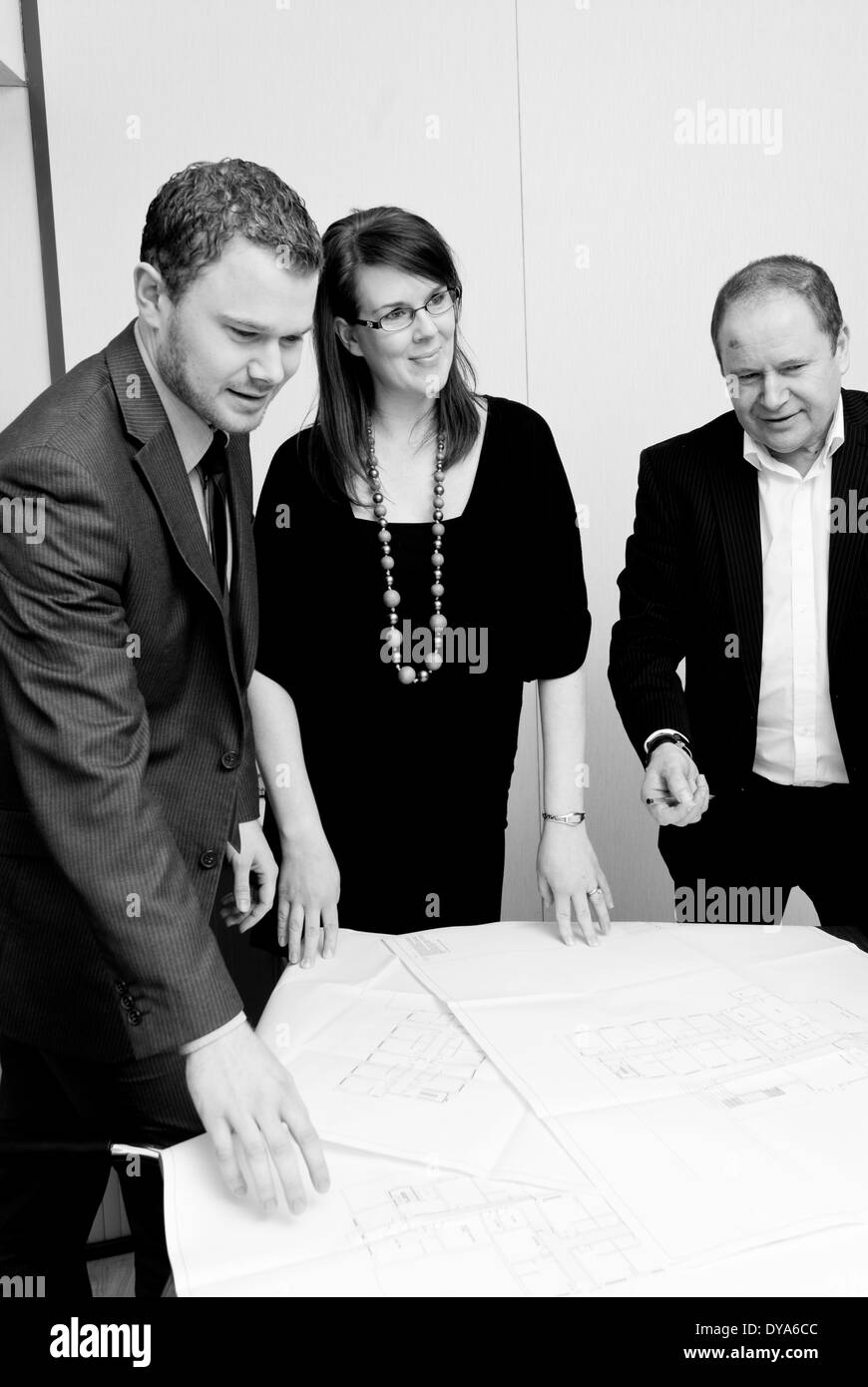 Tre persone in riunione intorno a un tavolo Foto Stock