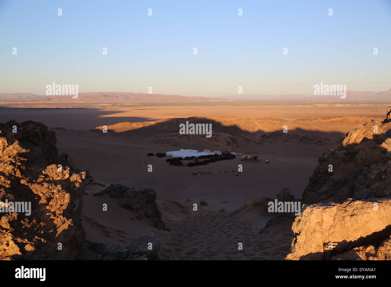 Cluster di tende in una vallata desertica nell'ombra di un alta duna di sabbia/hill durante le ore mattutine al di là di Atlas Mountain Range Foto Stock